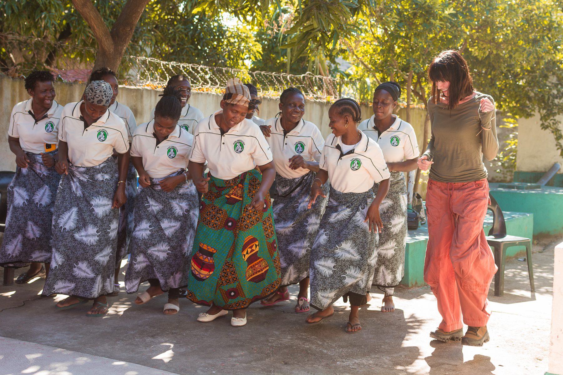 Community members and volunteers dancing together during a programme visit in Mozambique